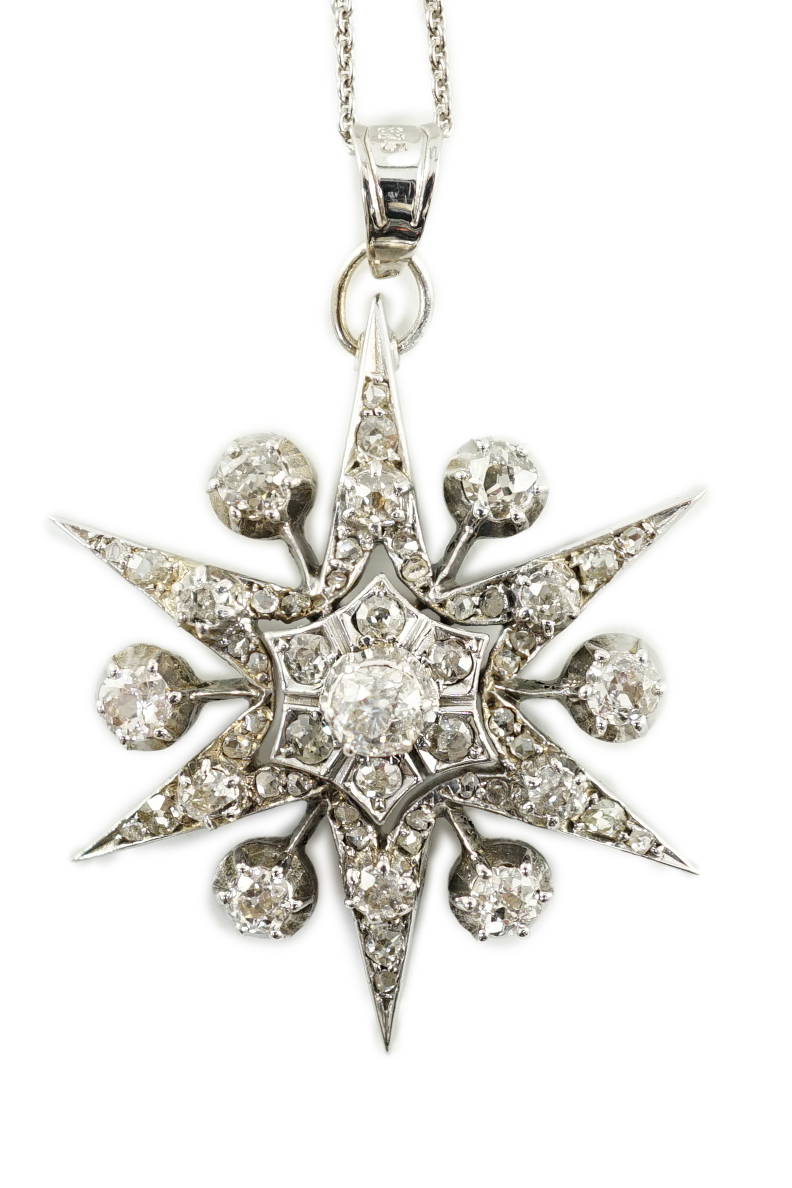 A Victorian white gold and diamond cluster set star burst pendant, on a later sterling chain